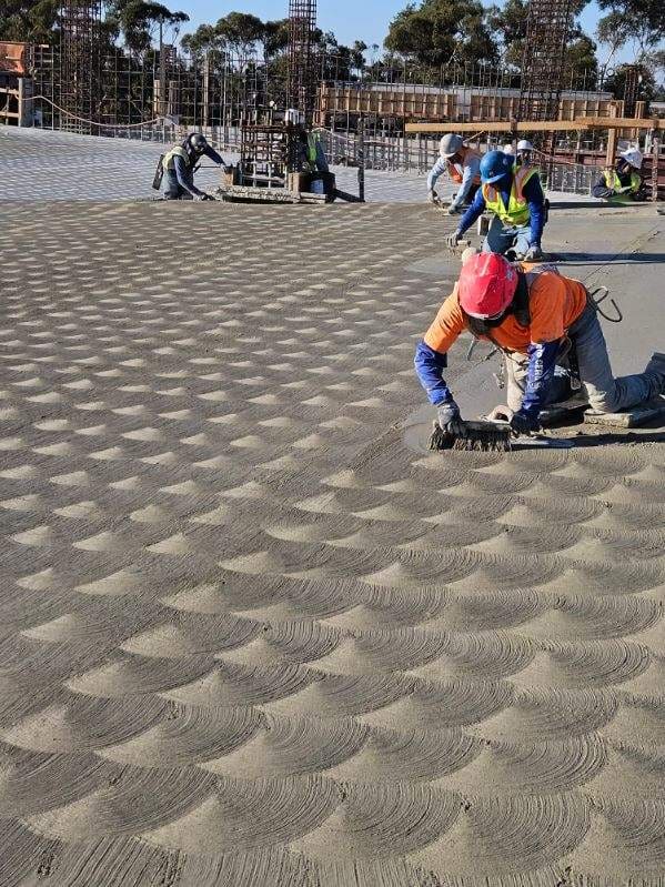 Crew member hand finishing a large commercial concrete slab