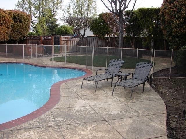 Stamped concrete pool deck with a brick border and lounge chairs