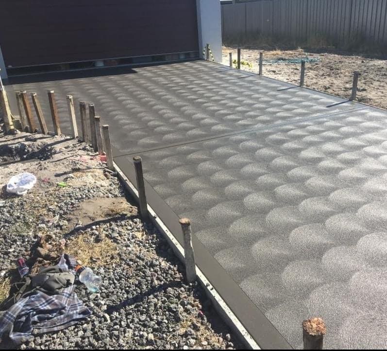 Fresh concrete driveway with a seashell broom finish alongside a house