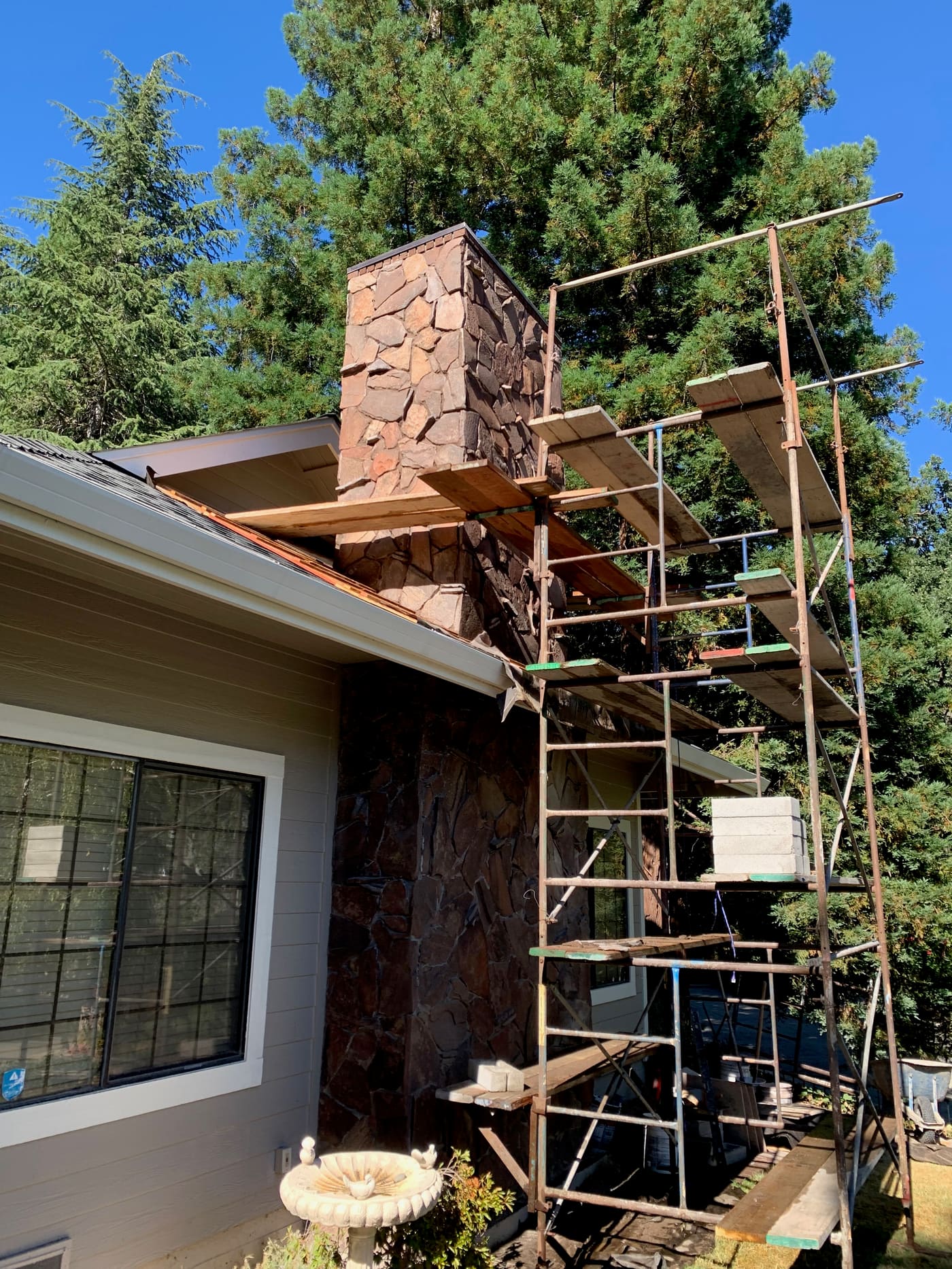 Stone veneer chimney being rebuilt on a house exterior