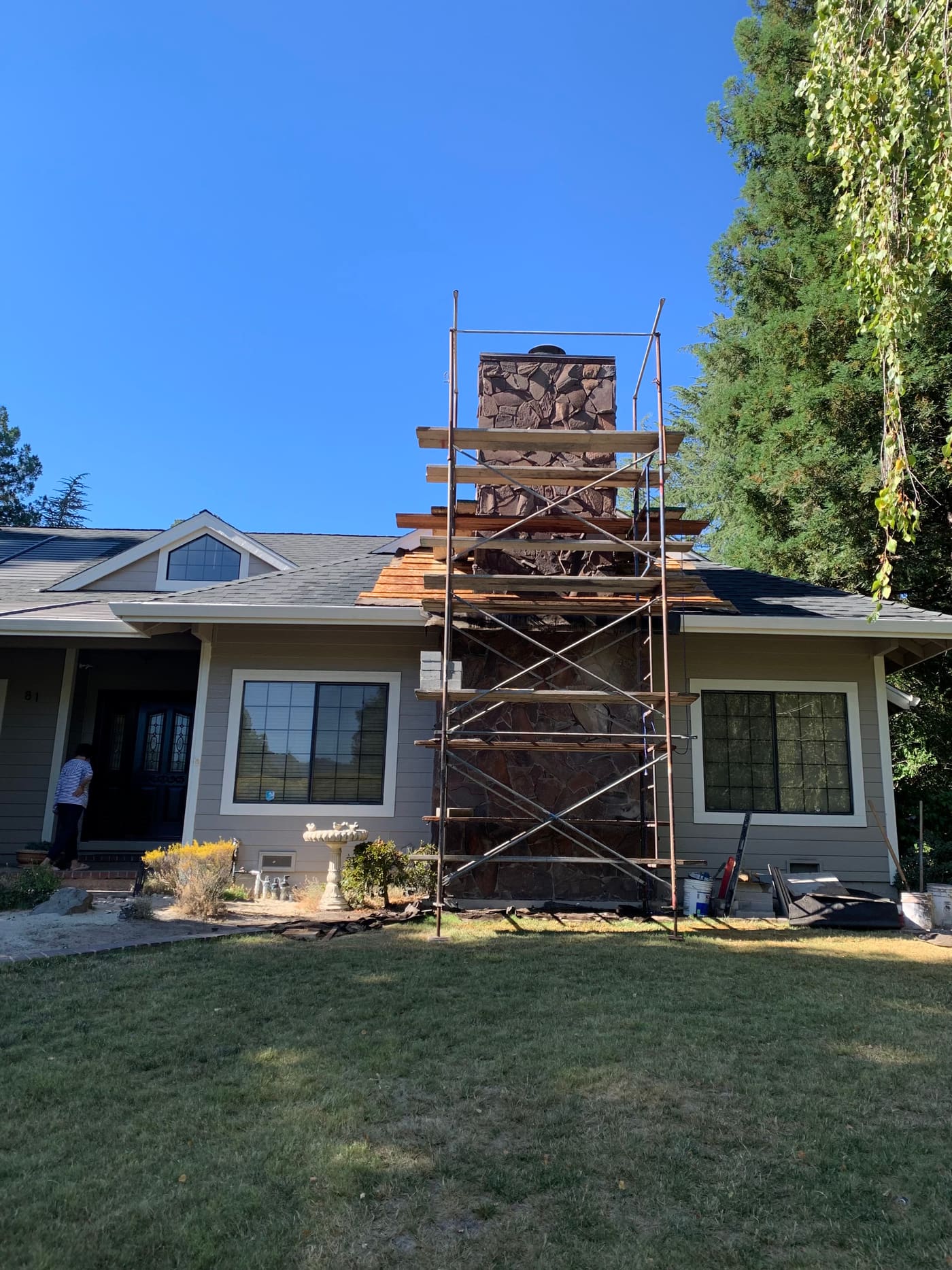 Stone chimney rebuild in progress with scaffolding