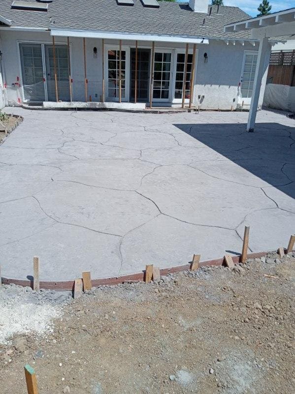 Large stamped concrete patio behind a house with a covered pergola