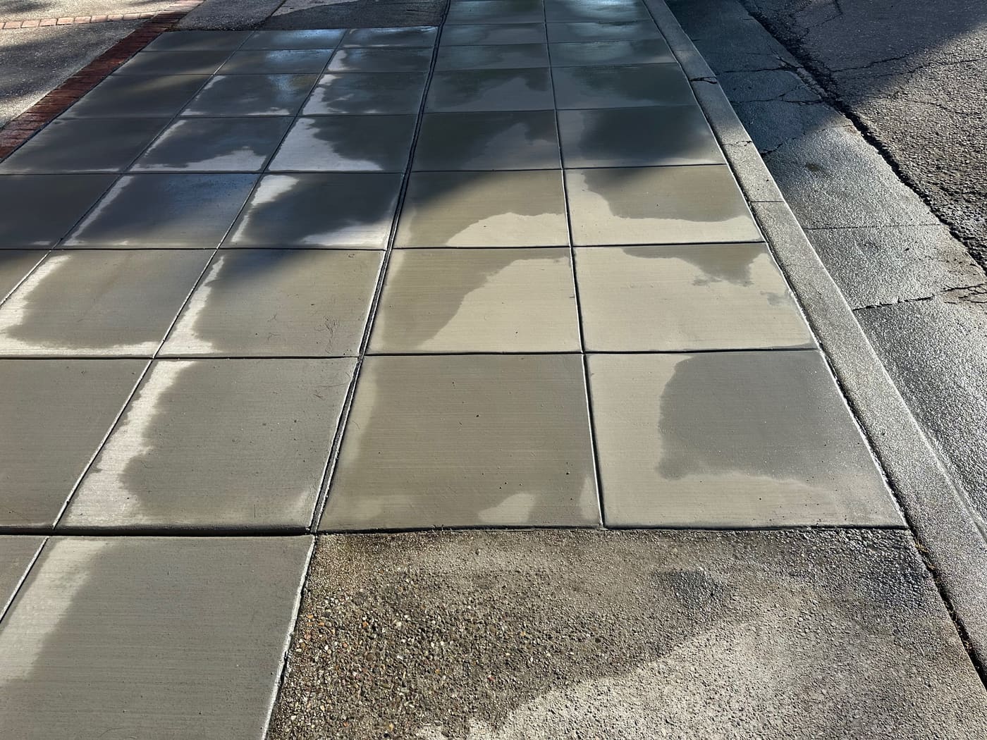 Charcoal colored concrete sidewalk poured with a brick border