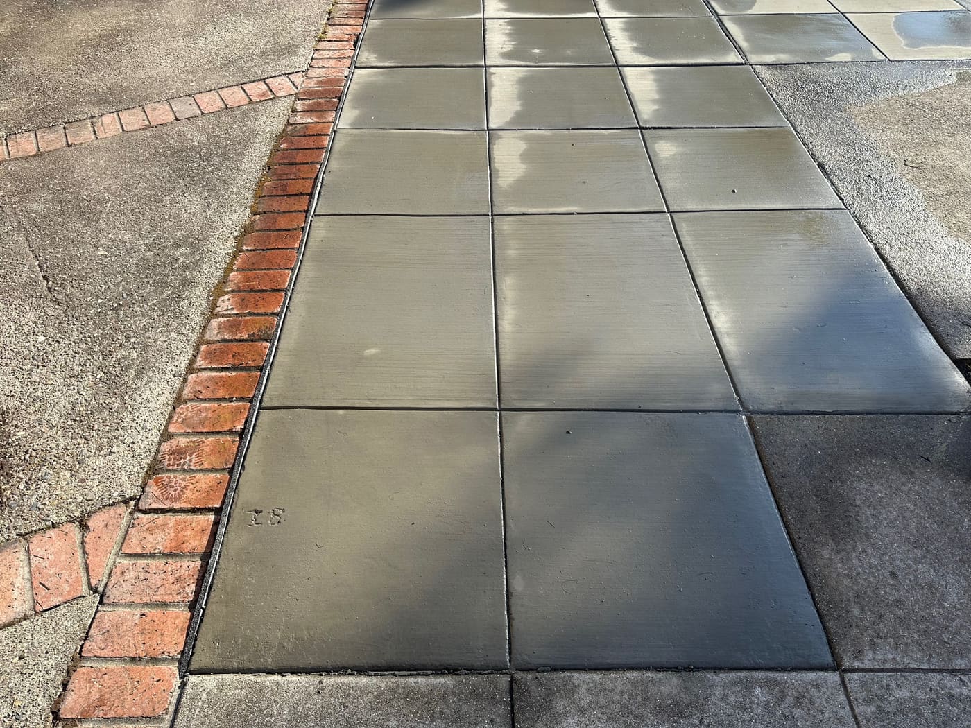 Charcoal colored concrete sidewalk with a brick border