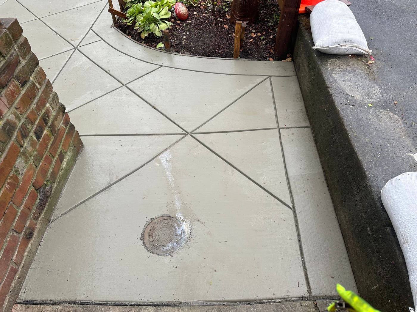 Decorative scored concrete walkway with triangular pattern next to a brick wall