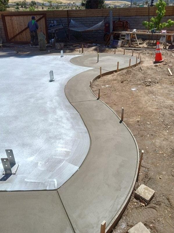 Curved concrete walkway under construction with form stakes