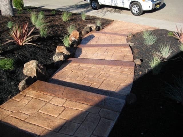 Custom stamped concrete walkway through landscaped planting beds