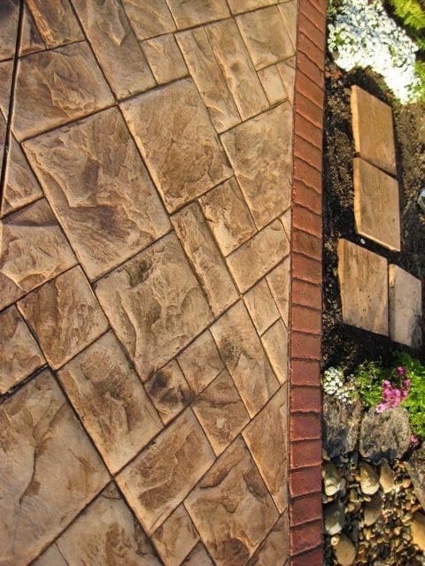 Custom stamped concrete walkway finished in a diagonal flagstone pattern with a brick border
