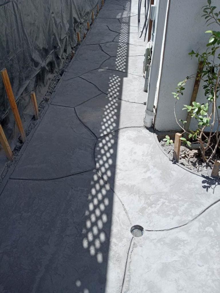 Narrow stamped concrete side-yard walkway alongside a house